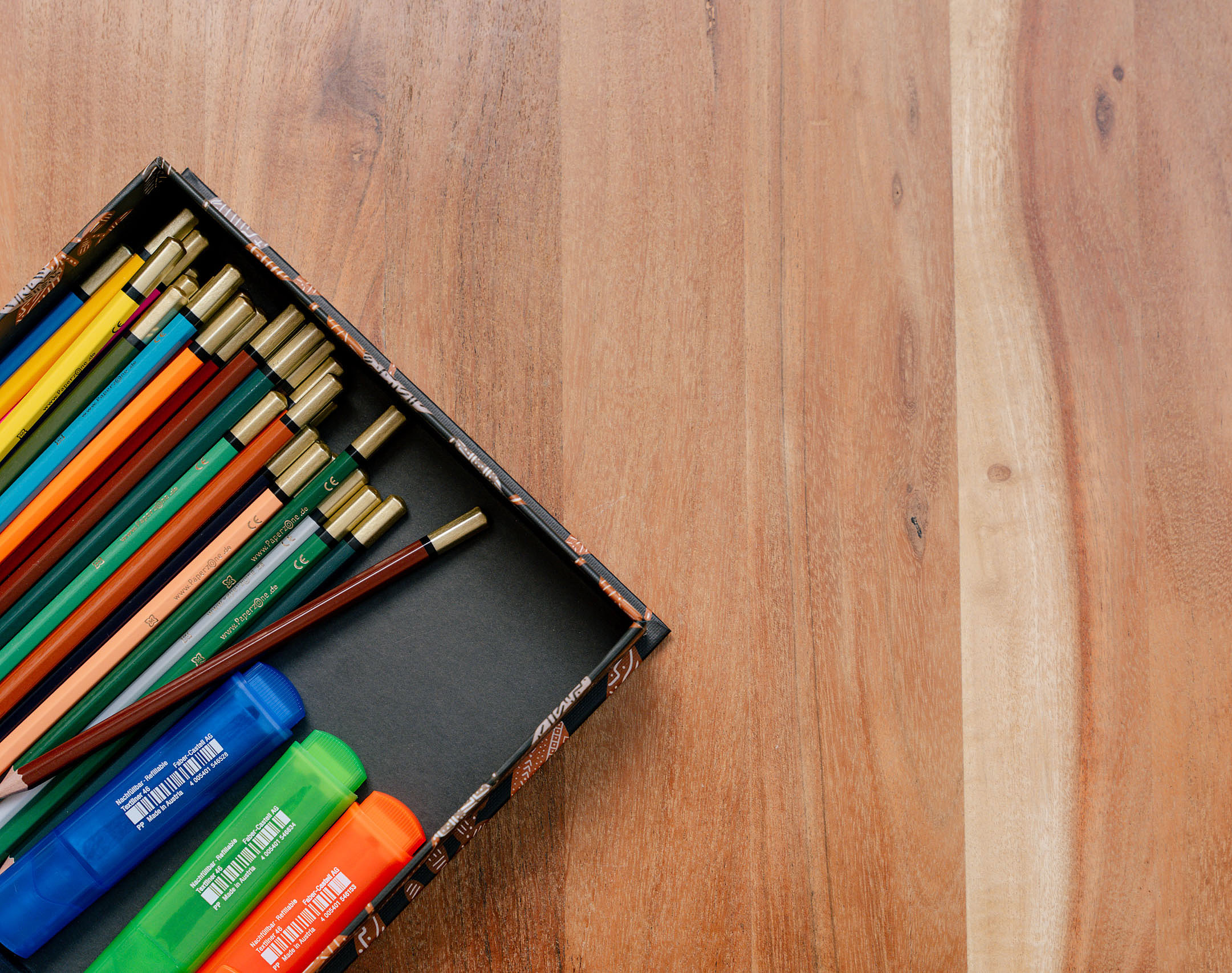 Farbstifte in einer Box auf einem Holztisch.