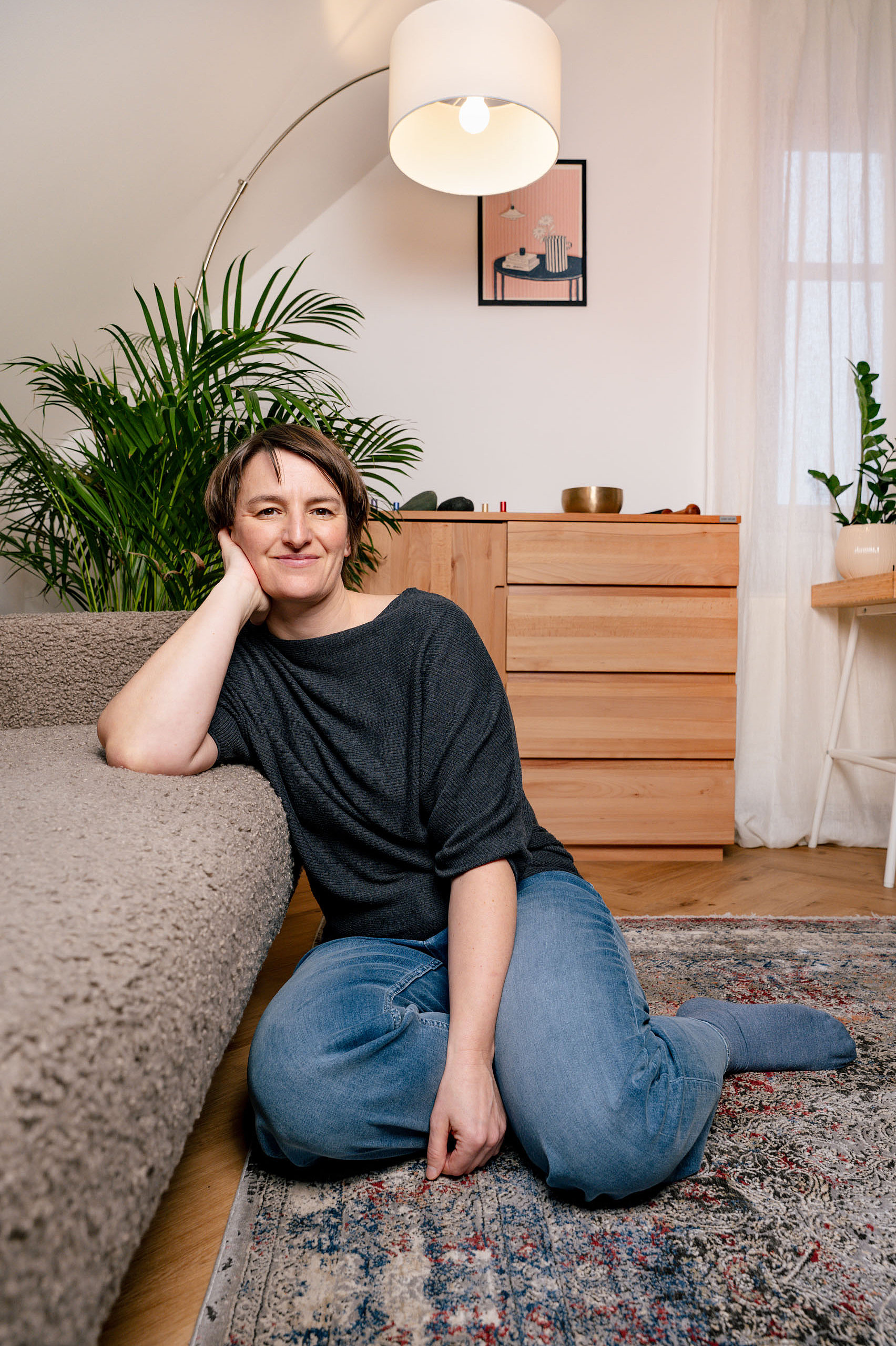 Dr. Johanna Sohm sitzt gemütlich auf dem Boden und lehnt sich an der Couch an.