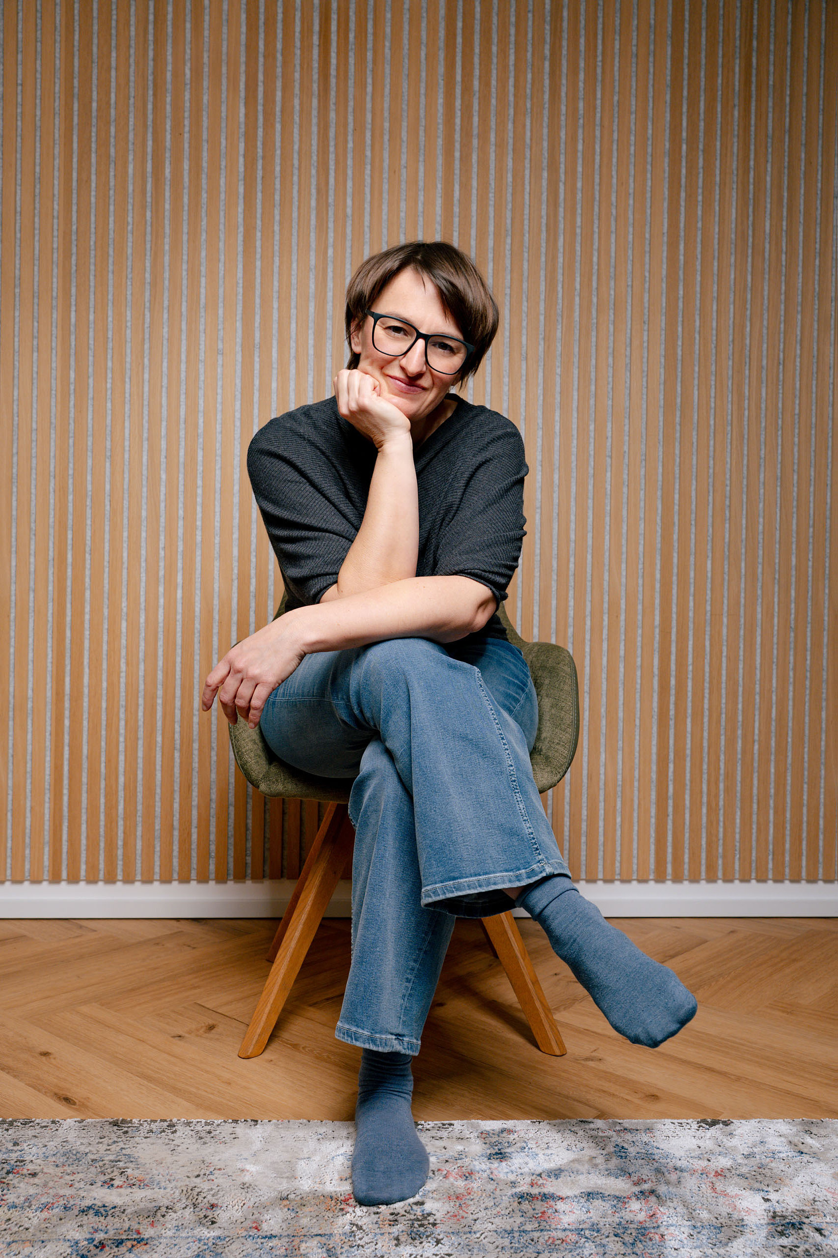 Dr. Johanna Sohm sitzt auf einem Sessel, hat ihr Kinn auf den Arm gestützt und die Beine überschlagen.