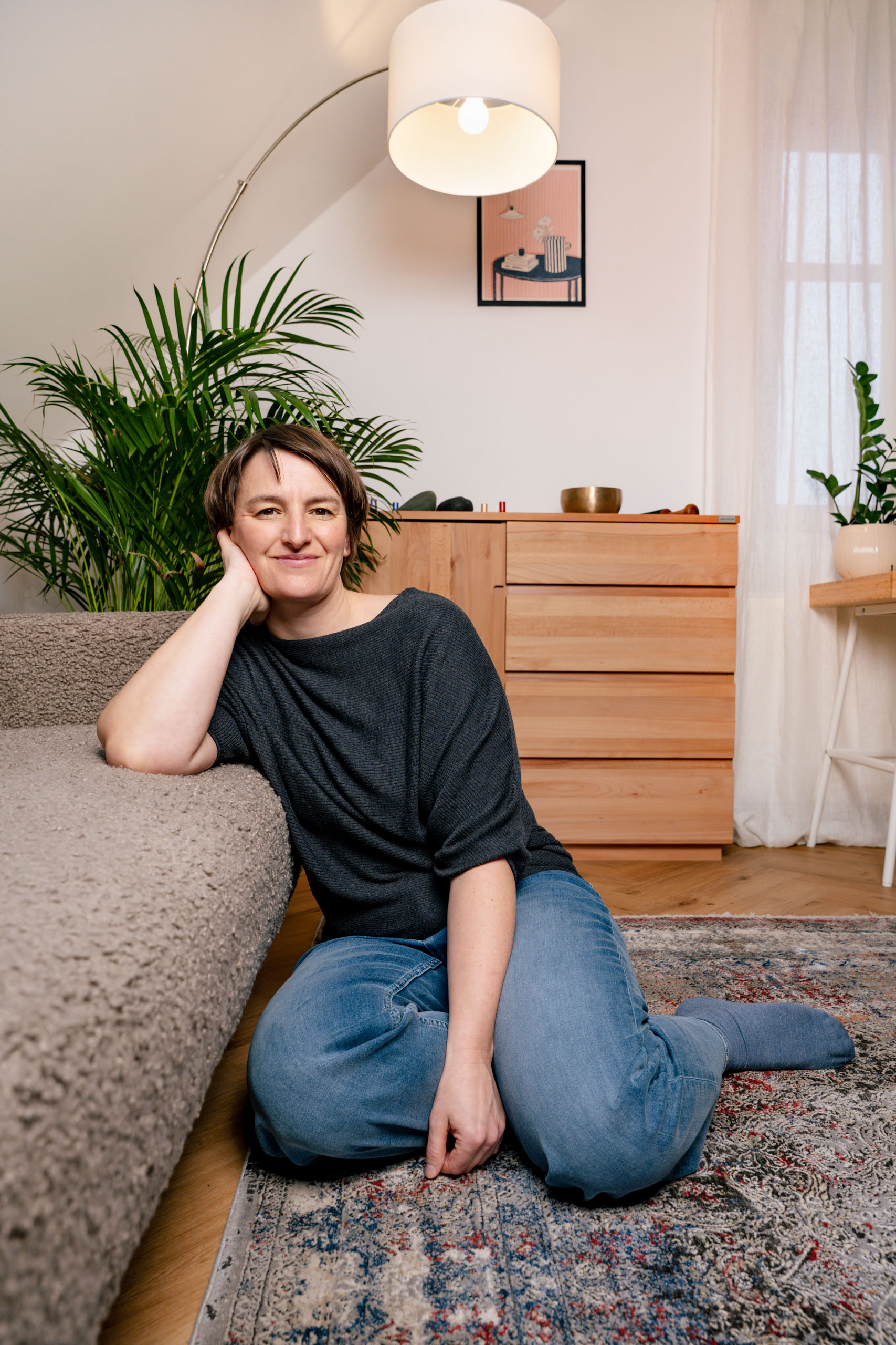 Dr. Johanna Sohm sitzt gemütlich auf dem Boden und lehnt sich an der Couch an.